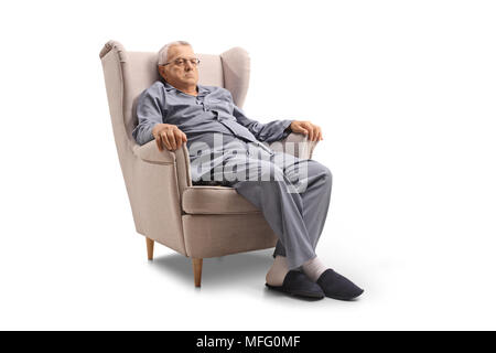 Mürrischen alten Mann im Schlafanzug in einem Sessel sitzt auf weißem Hintergrund Stockfoto