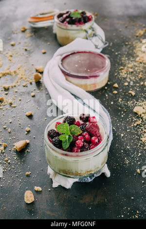 Käsekuchen mit Beeren gefüllt auf ein .jar über einen schwarzen Hintergrund rostig, nur natürliches Licht. Stockfoto