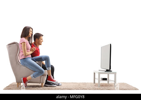 Junges Paar sitzt in einem Sessel und Fernsehen auf weißem Hintergrund Stockfoto