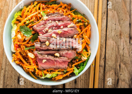 Bangkok Rindfleisch. Rindfleisch mit rotem Reis, geriebenen Karotten, Baby gem Salat, Erdnüsse & nam Jim Dressing Stockfoto