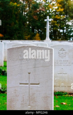 Grab eines Soldaten des Ersten Weltkriegs in Commonwealth War Graves Commission (Cwgc) Heiligtum Holz Friedhof mit einem Ehrenmal im Hintergrund. Stockfoto