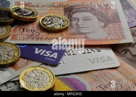 Britische zehn Pfund Noten und ein Pfund Münzen mit Visa Debit- und Kreditkarten close-up Stockfoto