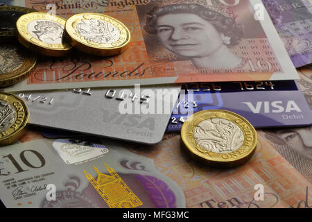 Britische zehn Pfund Noten und ein Pfund Münzen mit Visa Debit- und Kreditkarten close-up Stockfoto