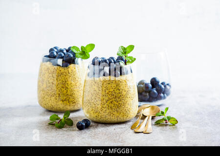 Chia Samen und Mango Püree Milchreis mit Beeren Heidelbeeren und Minze. vegan gesunde Frühstück oder Dessert auf den Tisch Stockfoto