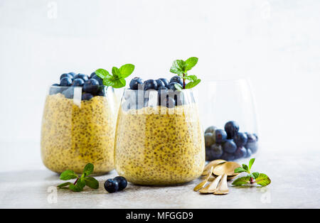 Chia Samen und Mango Püree Milchreis mit Beeren Heidelbeeren und Minze. vegan gesunde Frühstück oder Dessert auf den Tisch Stockfoto