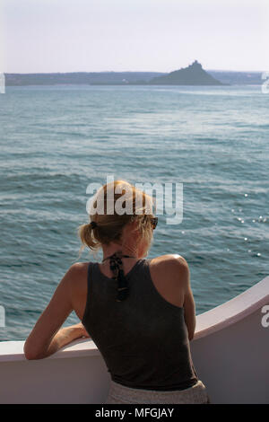 Hübsche, junge Frau im Vorstand des RMV cillonian III', en Route für die Scilly-inseln, mit St. Michael's Mount jenseits, Cornwall, UK. MODEL RELEASED Stockfoto