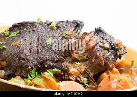 Ein Ochse Wange, die in einem Kupfer Pfanne und dann langsam gekocht in einem Slow Cooker mit Wurzelgemüse und mit gehackter Petersilie garniert angebraten wurde. Stockfoto