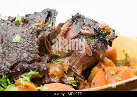 Ein Ochse Wange, die in einem Kupfer Pfanne und dann langsam gekocht in einem Slow Cooker mit Wurzelgemüse und mit gehackter Petersilie garniert angebraten wurde. Stockfoto