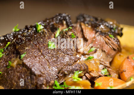 Ein Ochse Wange, die in einem Kupfer Pfanne und dann langsam gekocht in einem Slow Cooker mit Wurzelgemüse und mit gehackter Petersilie garniert angebraten wurde. Stockfoto