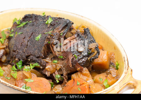 Ein Ochse Wange, die in einem Kupfer Pfanne und dann langsam gekocht in einem Slow Cooker mit Wurzelgemüse und mit gehackter Petersilie garniert angebraten wurde. Stockfoto