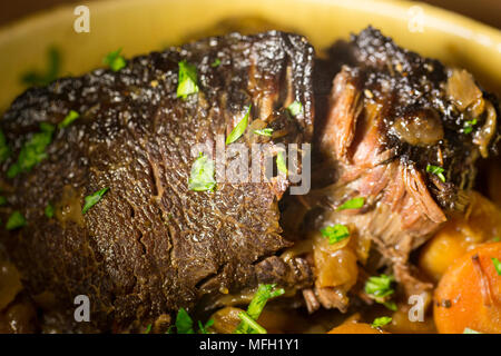 Ein Ochse Wange, die in einem Kupfer Pfanne und dann langsam gekocht in einem Slow Cooker mit Wurzelgemüse und mit gehackter Petersilie garniert angebraten wurde. Stockfoto