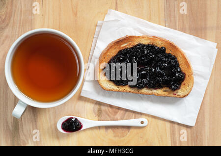 Tasse Tee und Toast mit Blaubeer-marmelade auf hölzernen Hintergrund, Ansicht von oben Stockfoto