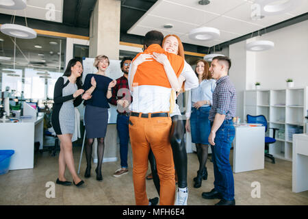 Büro Romanze Konzept. Zwei gemischte Rasse Liebhaber umarmt am Werk sind. Stockfoto