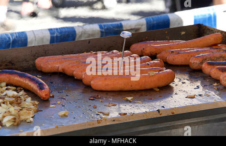 Große Hot Dogs auf einen Grill im Freien kochen, essen Thermometer in einem Weiner Temperatur zu überprüfen, ob die Mindestanforderungen für eine gesunde Speisen. Straßenhändler, Stockfoto
