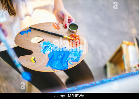 Frau artist Holding Palette mit Blau und Rot öl Farben und Malerei picrure closeup Stockfoto