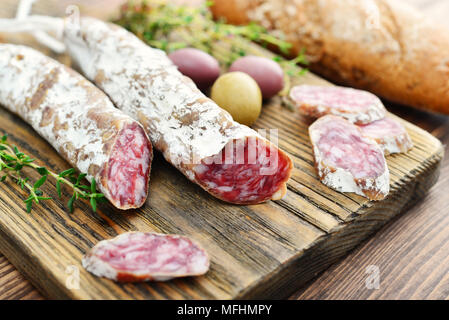 Spanisch schimmel Salami auf Schneidebrett mit Oliven und Brot über Holz- Hintergrund Stockfoto