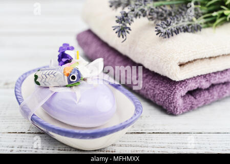 Lavendel Seife mit einer Einrichtung in Form von Motten in einer Soap Box mit einem Bouquet von Lavendel und Handtücher auf einer hölzernen Hintergrund Stockfoto