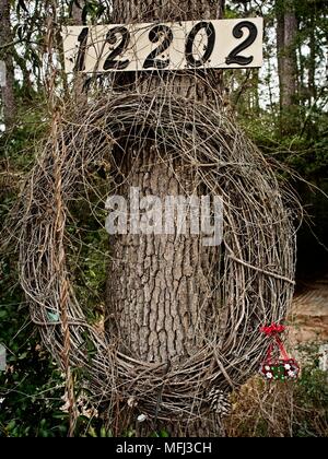 Weinkranz auf einem Baum mit einem Adressschild. Stockfoto