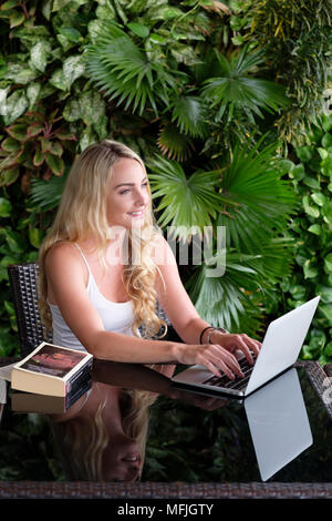 Junge kaukasier Frau Backpacker eine weiße Weste top und sitzen an einem Tisch in Asien, der an einem Notebook arbeitet, Vietnam, Indochina, Südostasien, Asien Stockfoto