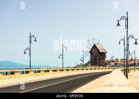 Nessebar, Bulgarien - leere Straße mit alten Straßenlaternen und hölzerne Windmühle am Isthmus von Nessebar in hellen, sonnigen Tag, dem Schwarzen Meer im Hintergrund Stockfoto