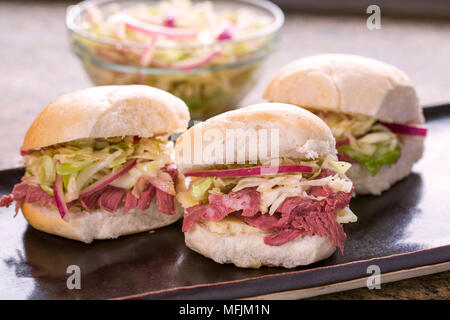 Zog Schweinefleisch Schieberegler auf einen braunen Neben einer Schüssel slaw. Stockfoto