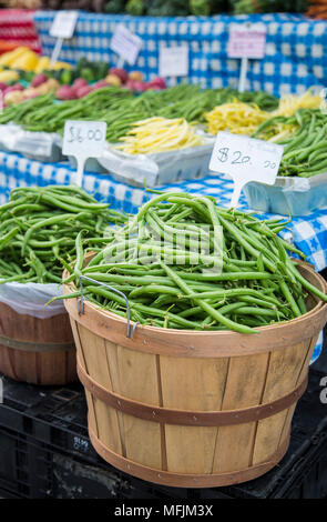 Ein scheffel Bohnen neben einem blauen Tischdecke auf ein Bauernmarkt überprüft. Stockfoto