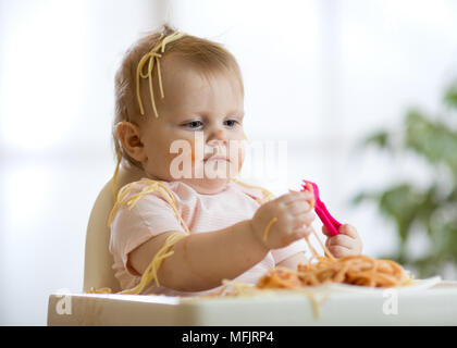 Cute funny Baby Mädchen Spaghetti zu Hause essen Stockfoto