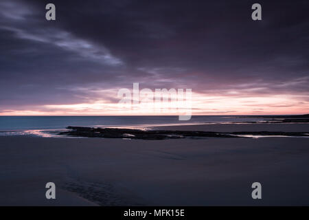 Dunstanburgh Castle, Northumberland. 26. April 2018. Dawn beginnt bei Embleton Bucht an einem bewölkten Morgen Credit: Dan Cooke Credit: Dan Cooke/Alamy leben Nachrichten Stockfoto