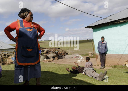 Matatiele, Eastern Cape, Südafrika. 10 Dez, 2017. Eine Mutter schaut sie Sonne, die auf das Gras und spielt mit seinem jüngeren Bruder liegt. Quelle: Stefan Kleinowitz/ZUMA Draht/Alamy leben Nachrichten Stockfoto