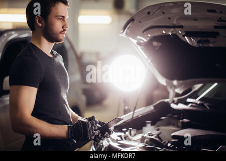 Konzentriert Mechaniker schreiben auf Zwischenablage in Werkstatt Stockfoto