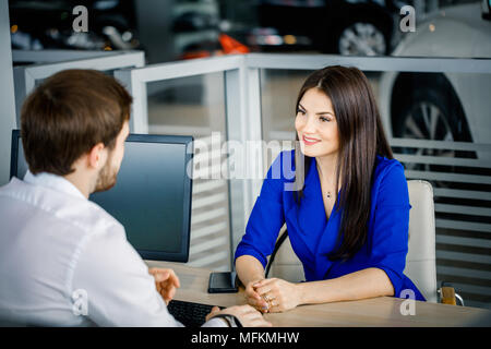 Vertriebsmitarbeiter sprechen zu einem glücklichen Frau Client versuchen zu überzeugen, neue Luxus Auto auf Hintergrund Stockfoto