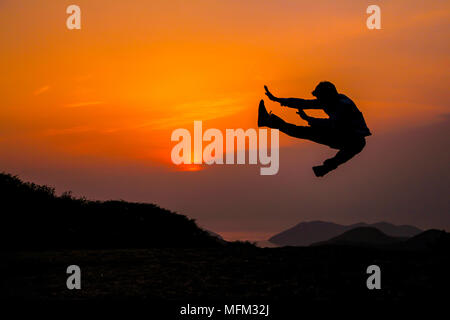 Silhouette der junge Mann springen mit der Dämmerung Himmel. Stockfoto