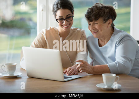 Lächelnd assistant Lehre ältere Frau, wie das Internet auf einem Laptop zu benutzen Stockfoto