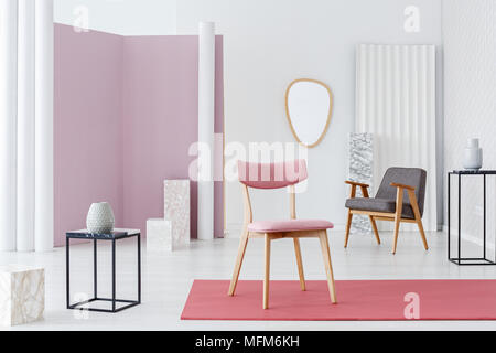 Rosa, Polsterstuhl, moderne Sessel und Marmor Würfel Dekorationen in einem weißen noblen und luxuriösen Wohnzimmer Interieur mit minimalistischem Design Stockfoto