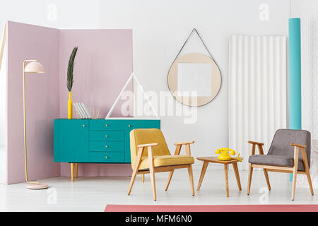Kreative, Pastell pink Stehleuchte in einem modernen und farbenfrohen retro Wohnzimmer Interieur mit Designer Dekoration und stilvolle Holzmöbel Stockfoto
