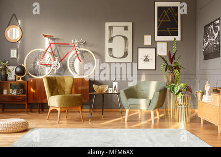 Schwarz Tisch zwischen grünen Sesseln im Retro-look Wohnzimmer Interieur mit roten Fahrrad und Poster Stockfoto