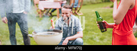 Panorama der Frau im roten Kleid Bier trinken während einer Gartenparty Stockfoto