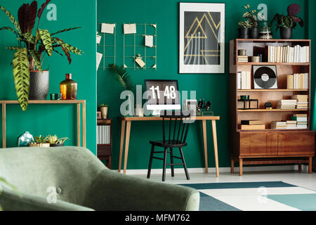 Hipster home office Schreibtisch mit Computer und eine antike, Holzregal in einem grünen, designer Wohnzimmer Einrichtung mit Pflanzen Stockfoto