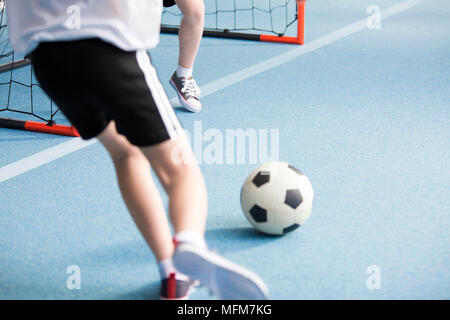 Nahaufnahme eines Jungen Fußball spielen mit seinem Freund an der Sporthalle Stockfoto