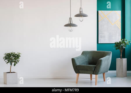 Konkrete Pflanzmaschinen, industrielle Kronleuchtern und einem dunklen, modernen Sessel in einem minimalistischen Wohnzimmer Innenraum Stockfoto