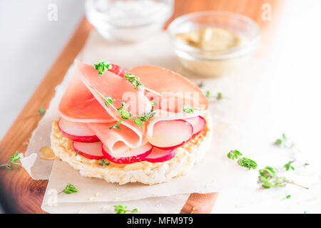 Knäckebrot gesunden Snack mit Parmaschinken, Rettich Scheiben, Senf, Salz und frischem Thymian. Einfaches Frühstück close-up auf weißem Hintergrund mit Kopie sp Stockfoto