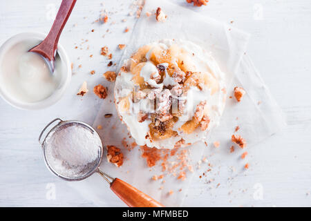 Knäckebrot Snack mit karamellisierten Bananen, Frischkäse, Puderzucker, griechischem Joghurt und Walnüsse. Gesundes Frühstück Konzept in einer High Key. Stockfoto