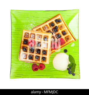 Belgische Waffeln mit Eis, Himbeeren und Heidelbeeren auf grün Glasplatte auf weißem Hintergrund, Birds Eye View Stockfoto