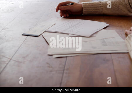 Person's Hand mit einem Stift in der Nähe ein Scheckheft mit Dokumenten auf dem Tisch Ref: CRB412 10004 040 obligatorische Credit: Gianni Diliberto/Photoshot Stockfoto