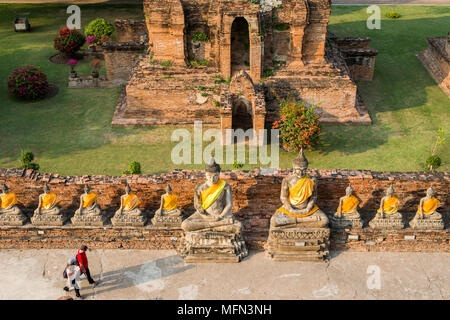 Zwei Besucher vorbei an einer Reihe von Buddha Statuen am Wat Yai Chai Mongkhon, einem buddhistischen Tempel aus dem 14. Jahrhundert, Ayutthaya, Thailand. Stockfoto