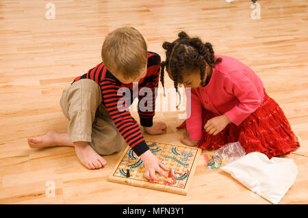 In der Nähe von zwei Kinder sitzen auf dem Boden und spielen Schlangen und Leitern Ref: Obligatorische Gutschrift: Stockfoto