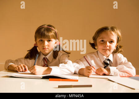 Porträt von zwei Mädchen sitzen zusammen schreiben Ref: Obligatorische Gutschrift: Stockfoto