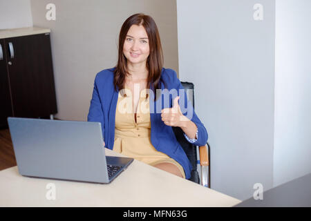 Freundliche Büro - Arbeitnehmer mit Daumen nach oben Vor dem Laptop. Stockfoto