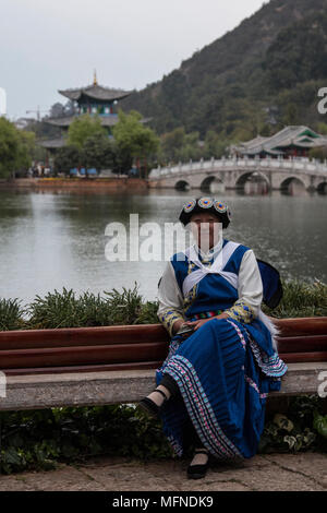 Lijiang, China - 23. März 2018: Chinesische Frau das Tragen eines traditionellen Bai Minderheit Kleidung sitzen vor dem Pool des Schwarzen Drachens in Lijiang Stockfoto