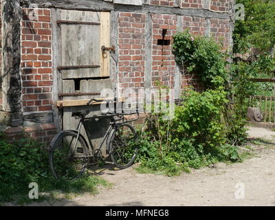 Altes Fahrrad hielten gegen eine alte hölzerne Tür, Suffolk, England Stockfoto